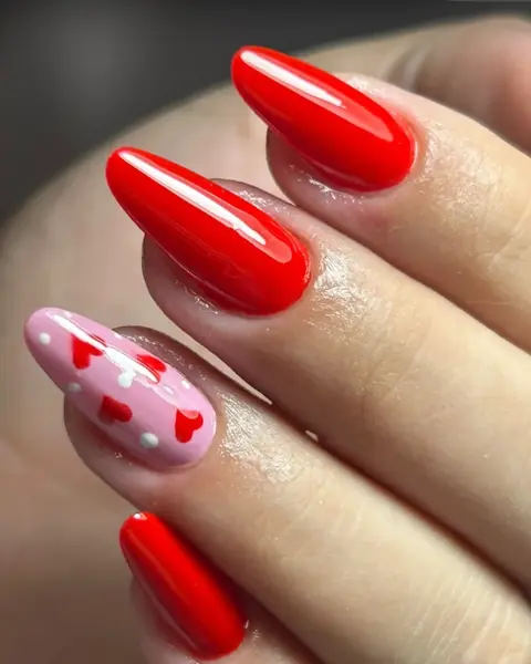Unhas vermelhas com uma unha decorada com corações